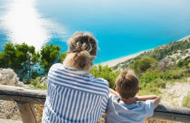Oğluyla birlikte güzel orta yaşlı bir kadın gün batımında güzel sahil şeridini seyrediyor.. 