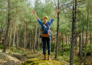 Sırt çantalı ve elini kaldırmış genç bir turist kadın. Yerel seyahat kavramı