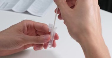 Geniz temizleme çubuğuyla hızlı antijen testi yapmak, tampon kesesinden tüpe sıvı dökmek, ellerini kapat..