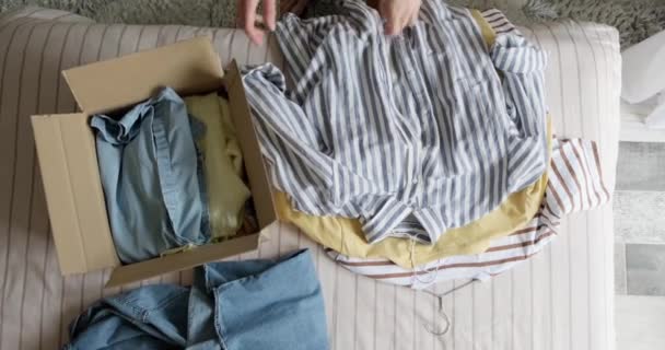 Frau packt gebrauchte Kleidung in Karton und verkauft sie im Internet weiter — Stockvideo