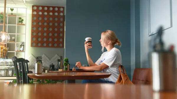 Νεαρή γυναίκα απολαμβάνει ένα φλιτζάνι καφέ σε ένα καφέ — Φωτογραφία Αρχείου