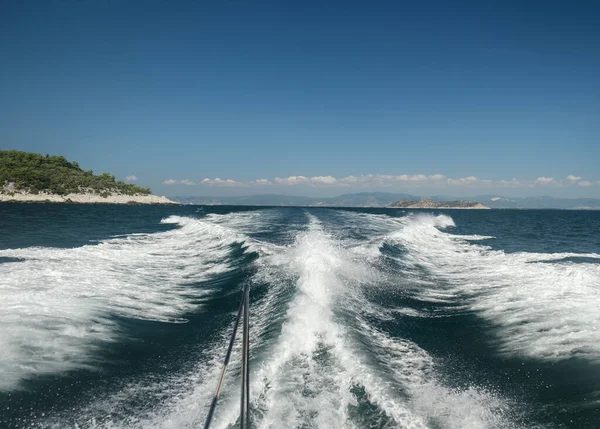 Yacht trail en la superficie del agua junto a la costa de la isla — Foto de Stock