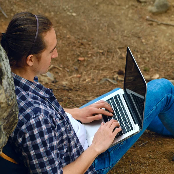 Adam ormanda oturuyor ve dizüstü bilgisayarla çalışıyor. — Stok fotoğraf