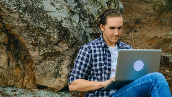 Adam ormanda oturuyor ve dizüstü bilgisayarla çalışıyor. — Stok fotoğraf