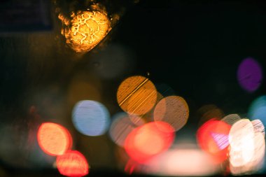 Şehirdeki cam camlara düşen yağmur damlalarıyla soyut bokeh bulanık arkaplan