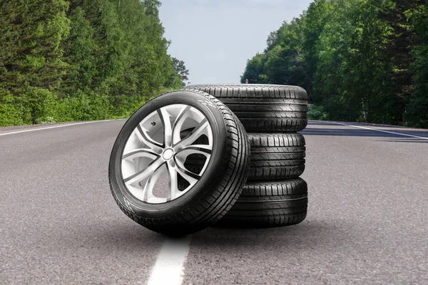 summer tires and alloy wheels set on an asphalt road. tire change season, auto trade, copy space, auto tuning and tire service
