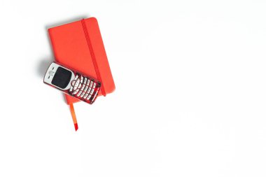 red mobile phone on a red notepad on a white background. planning, calling