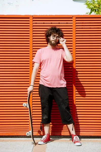 Man with skateboard on red background — Stock Photo, Image