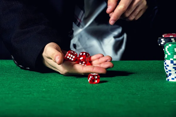 Male hand rolling five dice on green felt