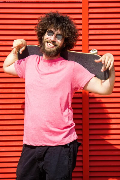 Man with skateboard on red background — Stock Photo, Image