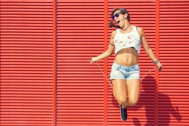 Woman jumping rope on red background