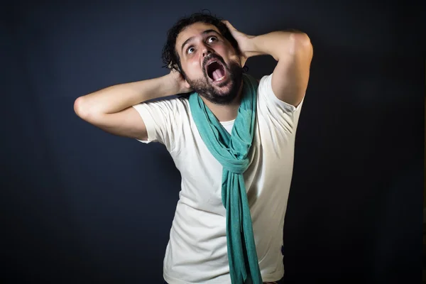 Young man screaming and pulling their hair on black background — Stock Photo, Image