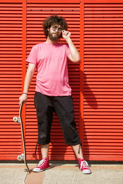 Man with skateboard on red background — Stock Photo, Image