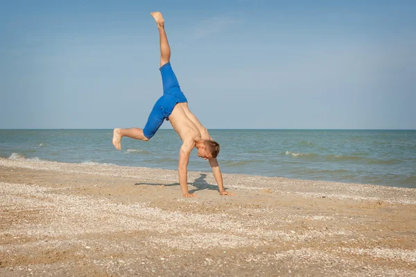 Junger Mann springt am Strand — Stockfoto