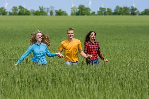 Junge glückliche Freunde laufen auf grünem Weizenfeld — Stockfoto