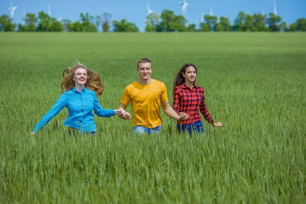 Junge glückliche Freunde laufen auf grünem Weizenfeld — Stockfoto