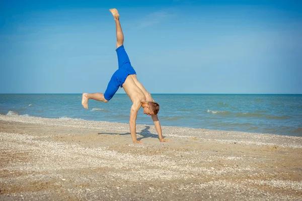 Junger Mann springt am Strand — Stockfoto