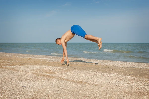 Junger Mann springt am Strand — Stockfoto