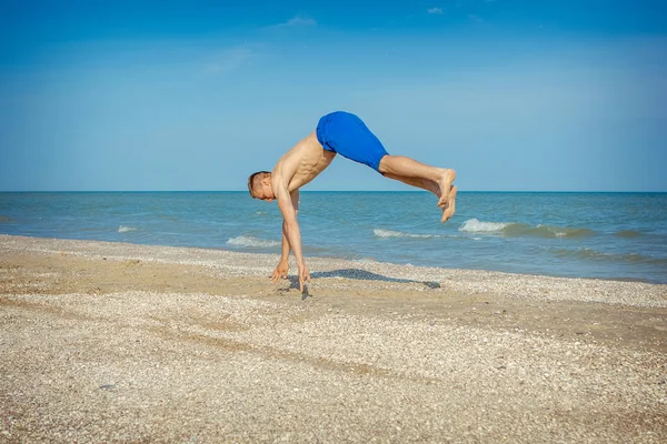 Junger Mann springt am Strand — Stockfoto