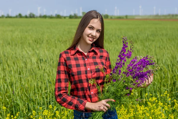 Vacker flicka på fältet med blommor — Stockfoto