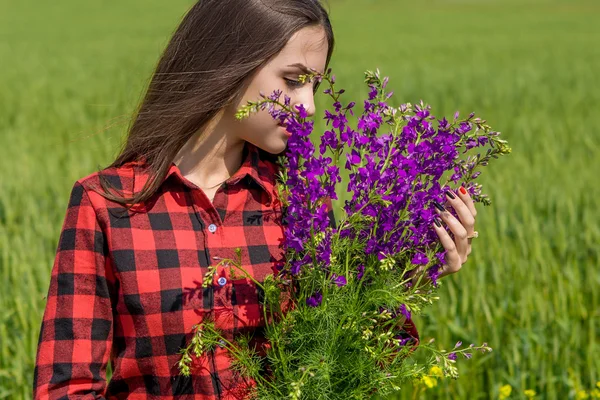 Bella ragazza sul campo con fiori di campo — Foto Stock