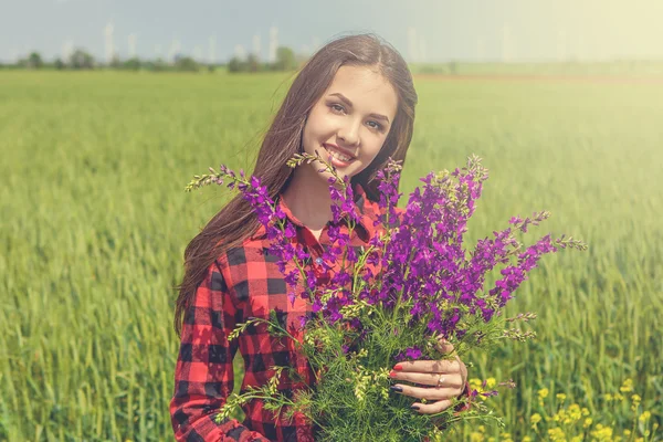 Bella ragazza sul campo con fiori di campo — Foto Stock