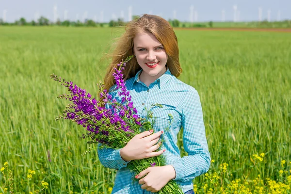 Vacker flicka på fältet med blommor — Stockfoto