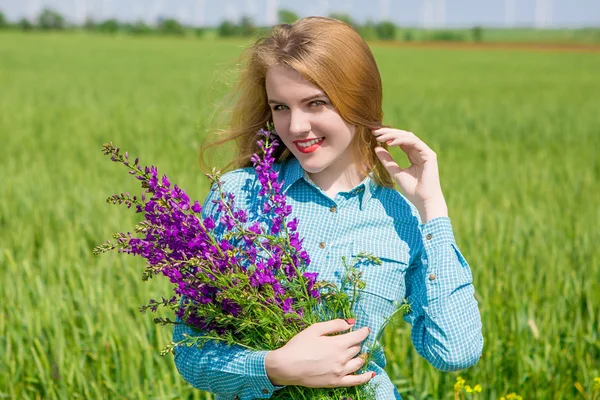 Vacker flicka på fältet med blommor — Stockfoto