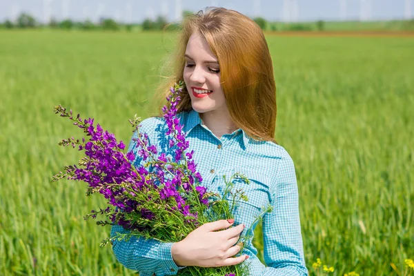 Bella ragazza sul campo con fiori di campo — Foto Stock