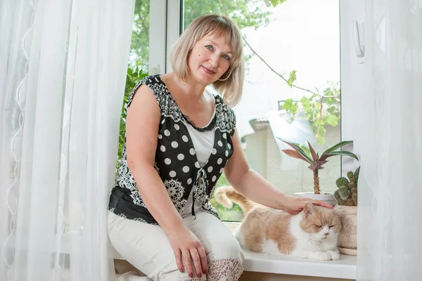 Mujer adulta con gato en ventana — Foto de Stock
