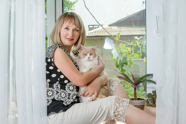 Donna adulta con gatto sulla finestra — Foto Stock