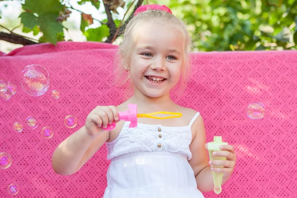 Счастливая маленькая девочка с мыльными пузырями — стоковое фото