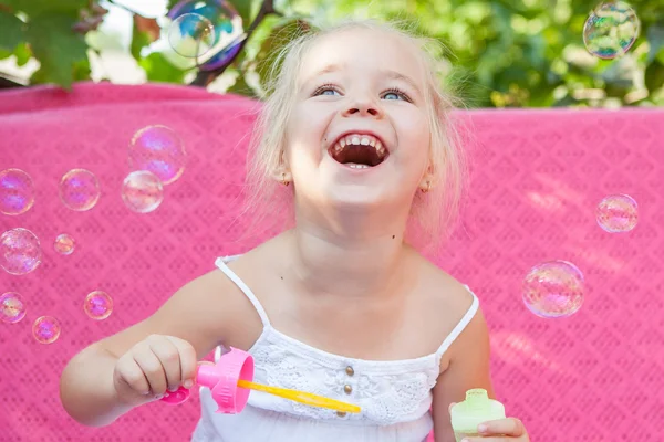 Счастливая маленькая девочка с мыльными пузырями — стоковое фото