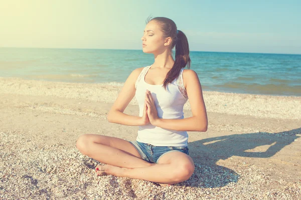 Young woman practicing yoga or fitness at seashore — Stock Photo, Image