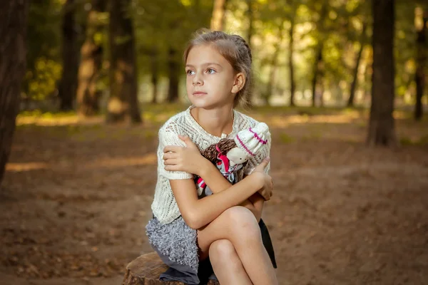 Γοητευτικό μικρό κορίτσι στο δάσος με κούκλα — Φωτογραφία Αρχείου