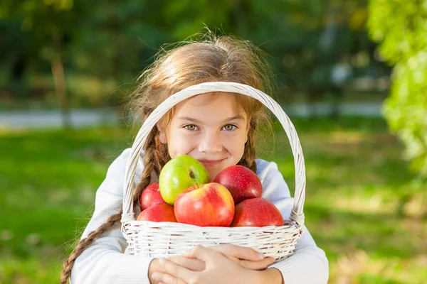 Niña sosteniendo una cesta de manzanas — Foto de Stock