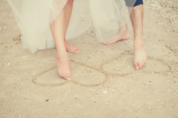 Paar Beine malen Herz auf Sand. — Stockfoto