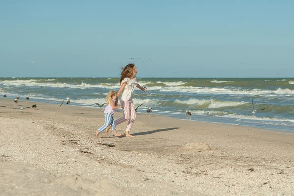 Мама и ее дочь веселятся, играя на пляже — стоковое фото