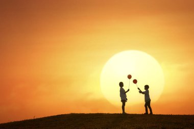 Balon tutan kız ve oğlanın silueti.