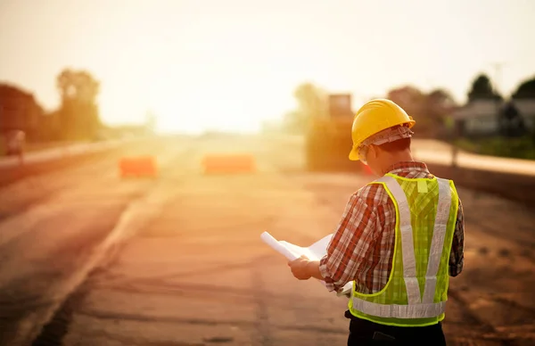 Engenheiro Segurando Planta Canteiro Obras Rodoviárias Com Fundo Máquinas Primeiro Imagem De Stock