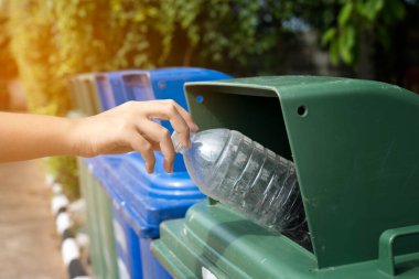 Kapalı el, boş plastik şişeyi geri dönüşüm kutusuna atıyor.