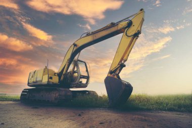 Günbatımı arka planında kazıcı ya da kepçe. İnşaat alanında ağır inşaat ekipmanları