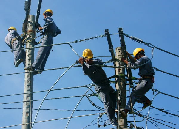 Asiatiska elektriker klättra högt, arbete på elektriska stolpe — Stockfoto