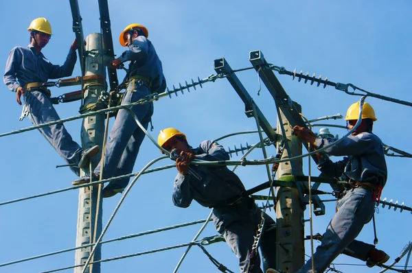 Asiatischer Elektriker klettert hoch, arbeitet an Strommast — Stockfoto