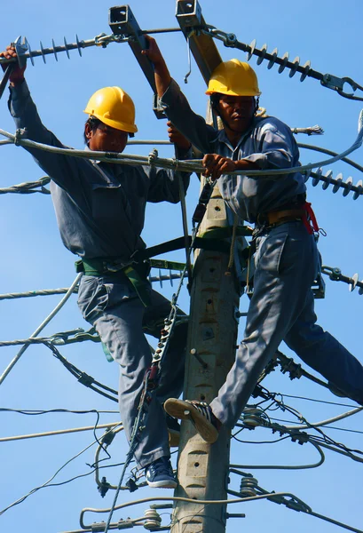 Asiatiska elektriker klättra högt, arbete på elektriska stolpe — Stockfoto