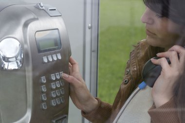 bir telefon kulübesinde bir telefon numarasını çevirmek