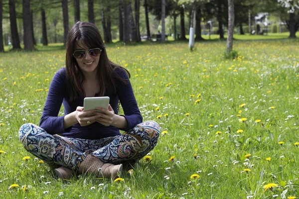 O fată cu o tabletă digitală în parc — Fotografie, imagine de stoc
