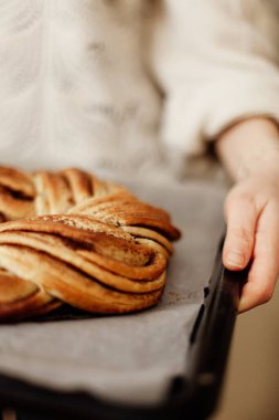 Kadınların elleri, örgü ya da daire şeklinde mis kokulu hamur işleri ile pişirme çarşaflarını tutarlar. Seçici odaklanma. Ev pastası. Yakın çekim.