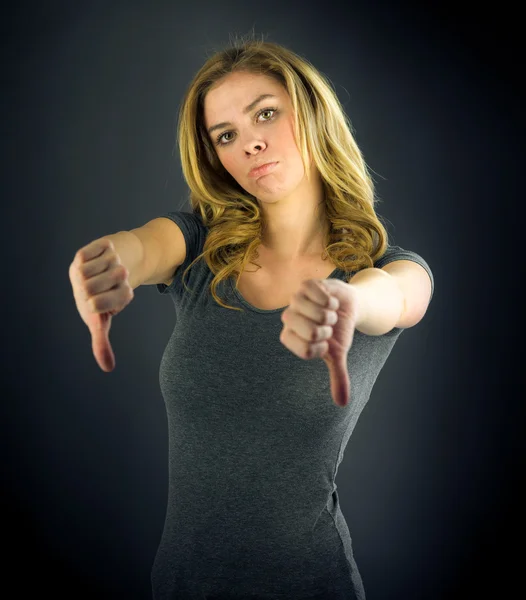 Kvinde kvinde gesturing tommelfingre ned tegn - Stock-foto