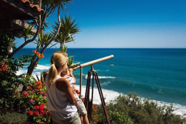 Anne ve oğlu teleskopla denize bakıyor.